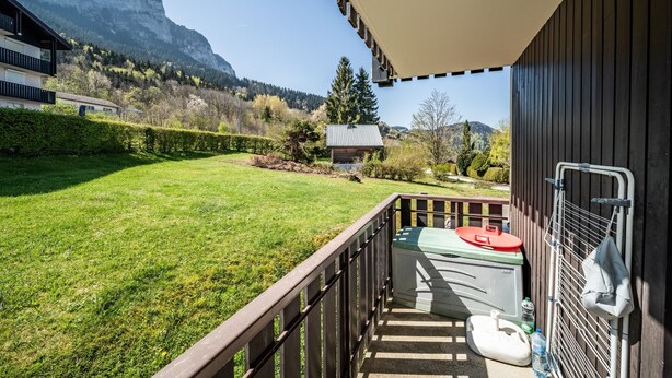 A balcony with a view of a mountain, a small shed, and a grassy yard.