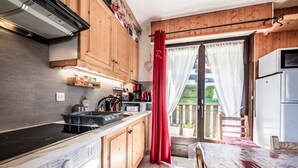 A compact kitchen with wooden cabinets, a washing machine, a microwave, and a refrigerator.