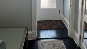 A hallway with a white door, a patterned rug, and a wall-mounted light fixture. - Silver Swan in Riverwest! (Milwaukee)
