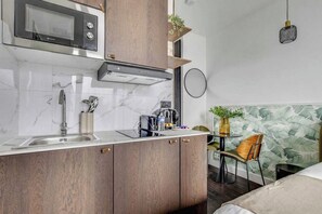 Cozinha compacta com micro-ondas, pia e armários de madeira.