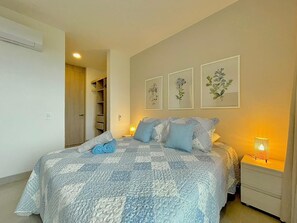 A bedroom with a bed, bedside tables, and wall art. - Luxury Apartment in Santa Marta | Ocean View (Santa Marta)