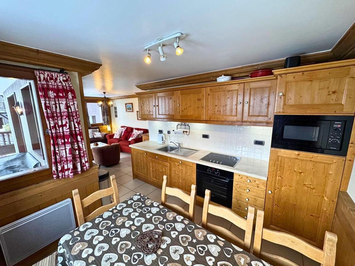 A kitchen with wooden cabinets, a microwave, a sink, and a dining table with chairs.