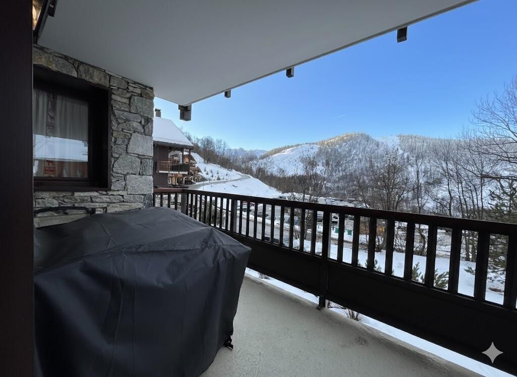 Un balcon fermé offrant une vue sur un paysage montagneux enneigé.