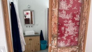 Una habitación con puerta corrediza de estilo rústico, un lavamanos, un espejo y una silla roja.
