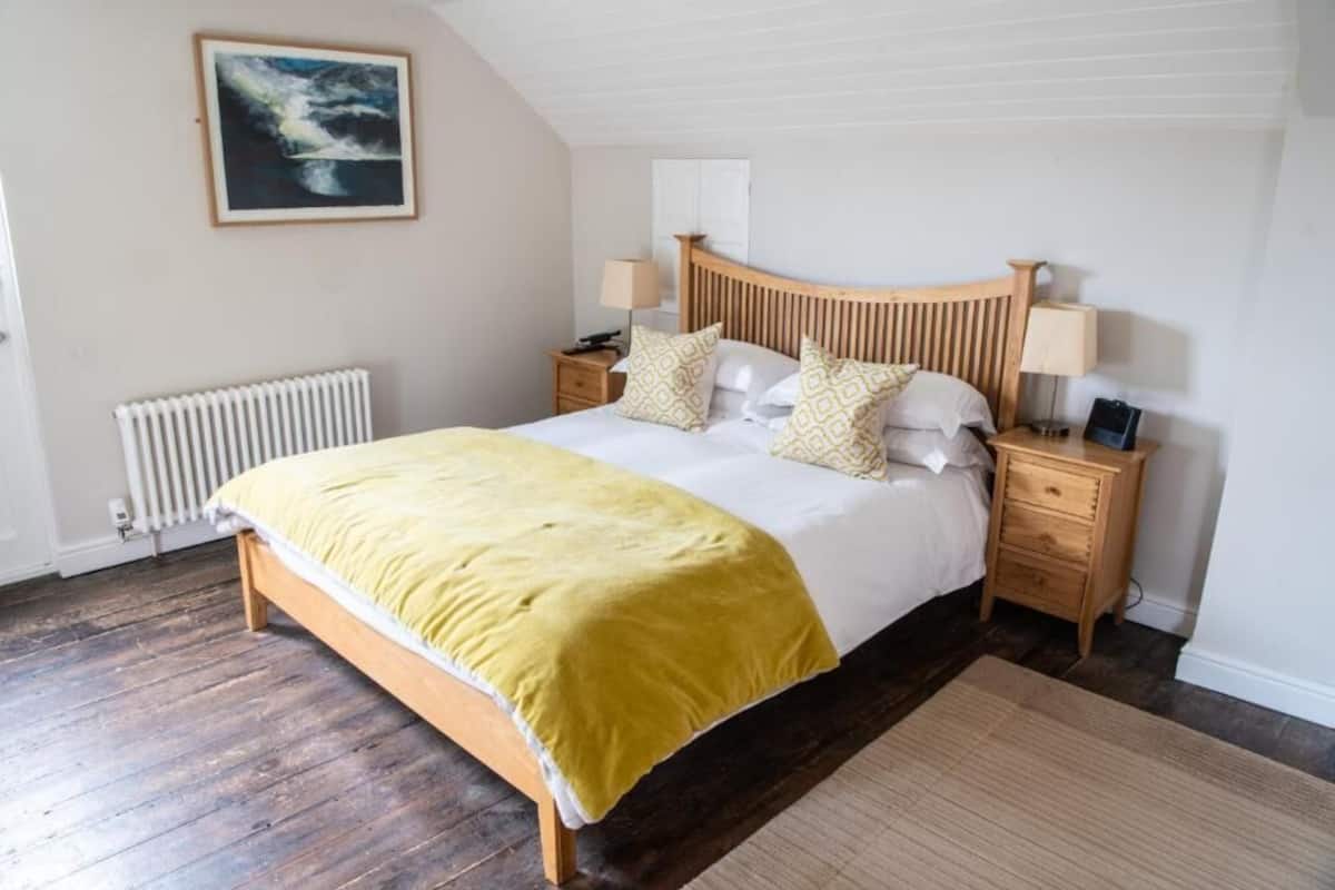 Una camera da letto con un letto in legno, un termosifone, un comodino con una lampada e un quadro appeso al muro.