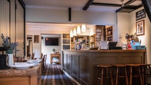A bar area with stools, a counter, and a television mounted on the wall. - Wheelwrights Arms (Monkton Combe)