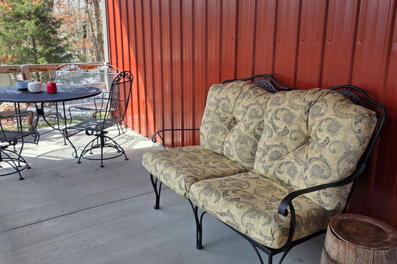 A patio with a cushioned bench, metal chairs, and a small round table.