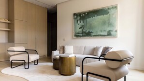 A modern living room with a sofa, two armchairs, a coffee table, and a large abstract painting on the wall. - Luxury Flat -2br/6p- Madeleine/saint Honore (Paris)