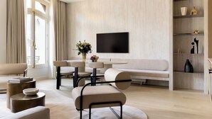 A modern living room with a sofa, chairs, a coffee table, a flat-screen TV, and a bookshelf. - Luxury Flat -2br/6p- Madeleine/saint Honore (Paris)
