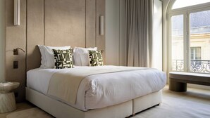 A bedroom with a large bed, a bedside table, a bench, and a view of the outside. - Luxury Flat -2br/6p- Madeleine/saint Honore (Paris)