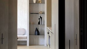 A modern interior with a wooden floor, a white sofa, and a minimalist shelving unit with various objects. - Luxury Flat -2br/6p- Madeleine/saint Honore (Paris)