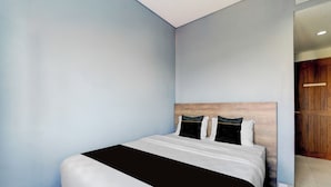 A bedroom with a bed, light blue walls, and a wooden headboard. - Colletion O near Living Plaza Cirebon fo (West Cirebon)