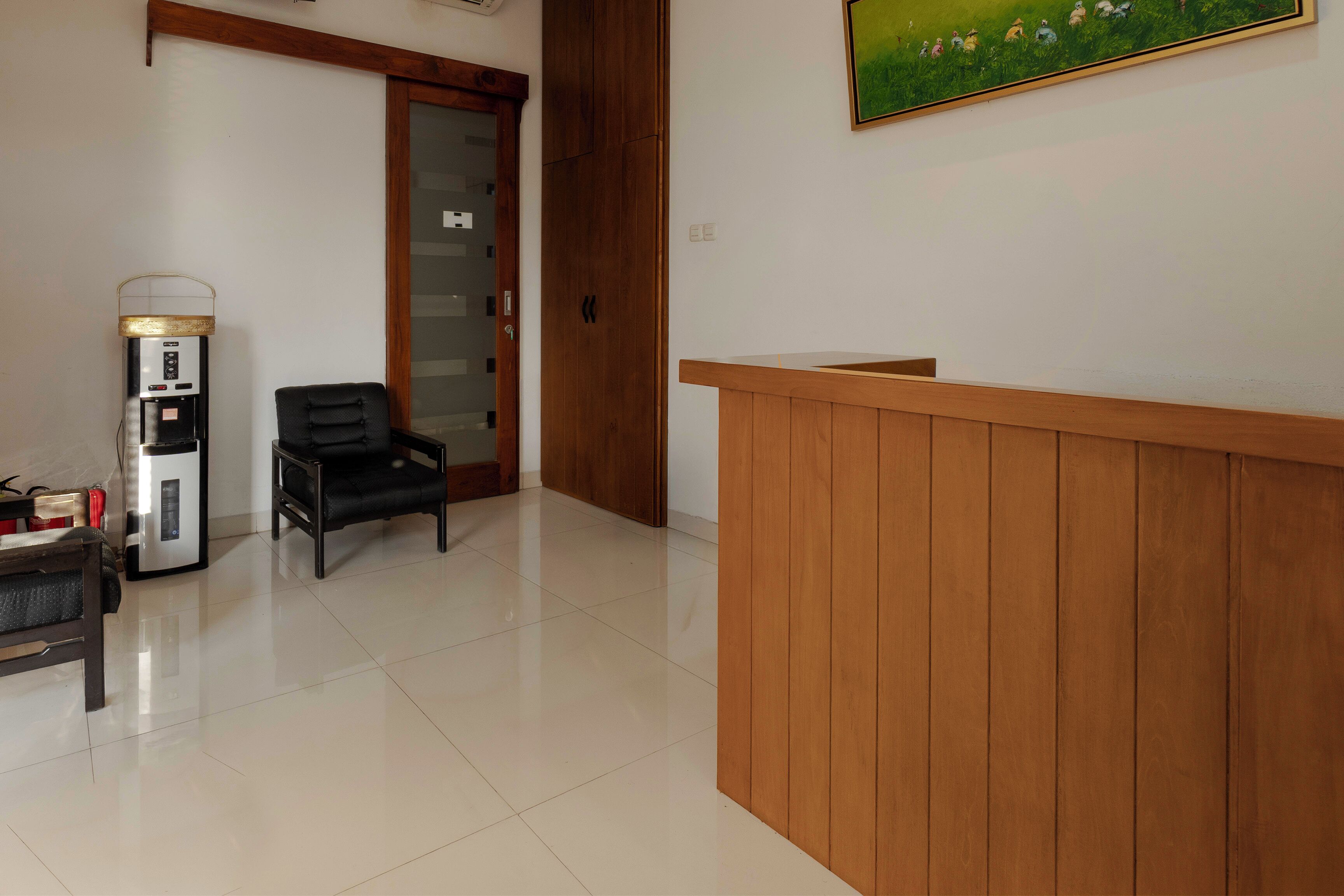 A reception area with a wooden counter, a water dispenser, a black chair, and a door with a glass panel.