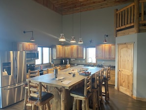 A spacious kitchen with wooden cabinets, stainless steel appliances, and a large island with bar stools.