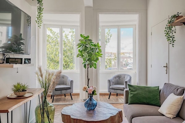 A modern living room with a large window, two armchairs, a sofa, a coffee table, and a TV mounted on the wall. - Champs de Mars - Chic 4-bedroom T5, fully equipped (Toulon)