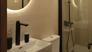 A modern bathroom with a white sink, black faucet, and a glass-enclosed shower. - Collection Las Ventas Apartamento E Cerca de la Plaza de Toros (Madrid)