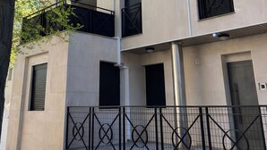 A two-story building with a beige facade, black window shutters, and a metal fence. - Collection Las Ventas Apartamento E Cerca de la Plaza de Toros (Madrid)