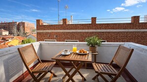 A rooftop terrace with a wooden table and two chairs, a basket, a plate with croissants, a cup, and a glass of orange juice. - Collection Las Ventas Apartamento E Cerca de la Plaza de Toros (Madrid)