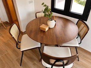 A round wooden dining table with four chairs, a vase with a plant, and a small box on the table. - Collection Las Ventas Apartamento E Cerca de la Plaza de Toros (Madrid)