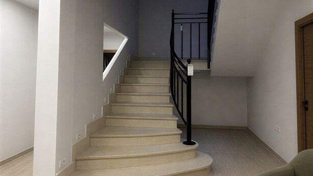 A staircase with a handrail, a light-colored floor, and a green sofa in a room with white walls. - Collection Las Ventas Apartamento E Cerca de la Plaza de Toros (Madrid)