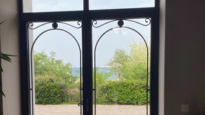 A double door with a view of a garden and a body of water. - Dream stay at Tamaris - Studio with sea view (La Seyne-sur-Mer)