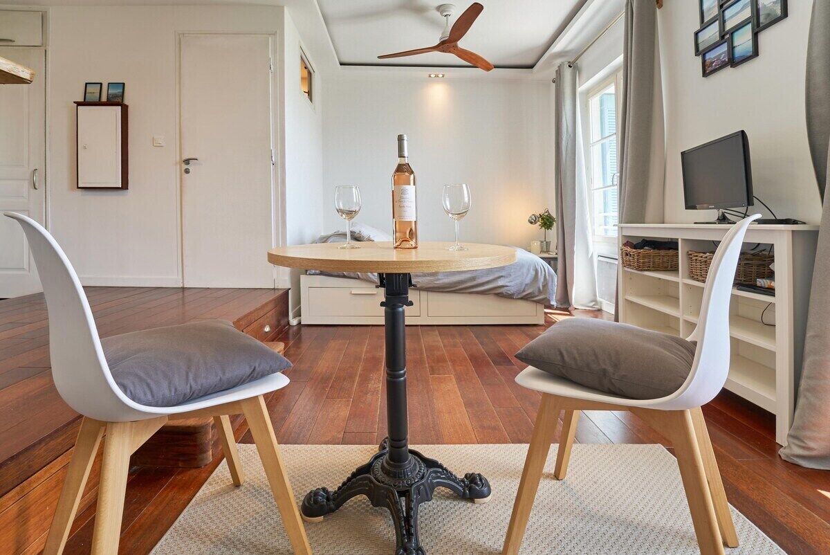 A room with a round table, two chairs, a wine bottle, and glasses.