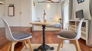 A room with a round table, two chairs, a wine bottle, and glasses.