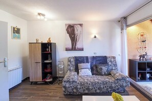 Ein modernes Wohnzimmer mit einem gemusterten Sofa, einer Holzkabine, einer Wandregal und einem großen Elefantenbild.