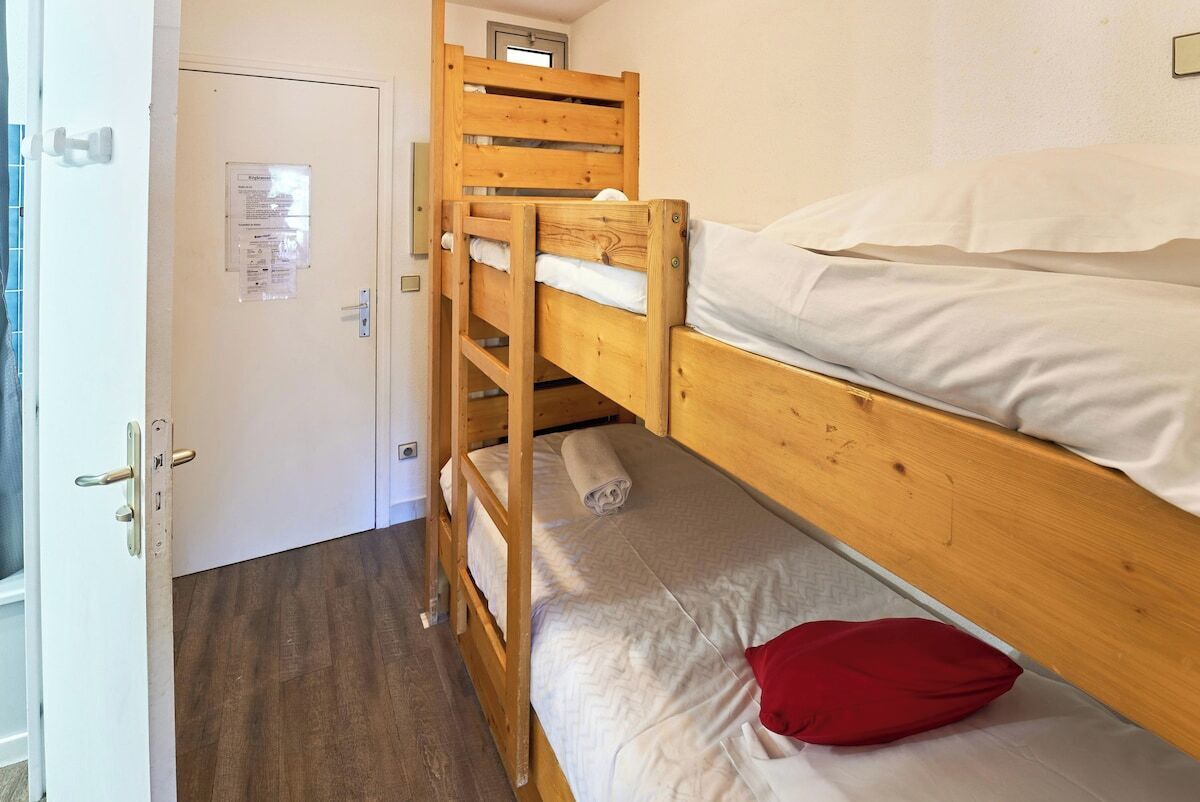 A bunk bed room with a wooden ladder, a white door, and a small window.