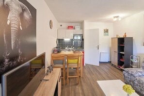 A compact living space with a dining area, kitchenette, and a sofa. - Évasion aux Cystes - Swimming pool & terrace (Sanary-sur-Mer)