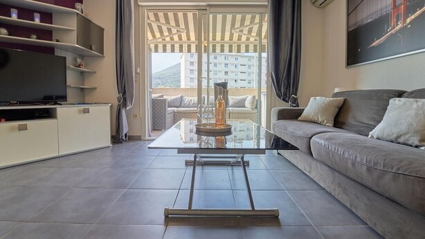 Un salon moderne avec une table basse en verre, un canapé et un téléviseur.