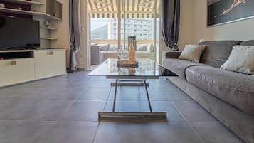 Een moderne woonkamer met een glazen salontafel, een bank en een televisie.