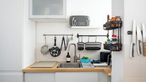 Uma cozinha com bancada de madeira, pia, suporte para panelas pendurado, torradeira e um armário para temperos.