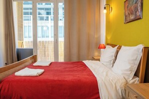 A hotel room with a bed, a nightstand, a lamp, and a window with curtains. - Getaway between town and sea, sunny terrace (Toulon)