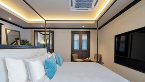 Moderni hotellihuone, jossa on suuri sänky, taulutelevisio, työpöytä tuolilla ja ovi, joka johtaa parvekkeelle.