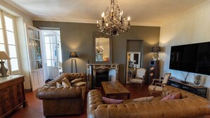 A living room with leather sofas, a chandelier, a fireplace, and a television. - Charming mansion (Toulon)
