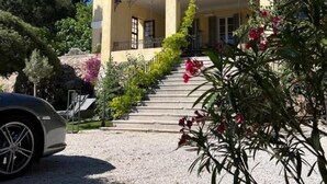 A building with a balcony, steps leading to the entrance, and surrounding greenery. - Charming mansion (Toulon)