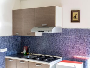A kitchen with a gas stove, cabinets, and a tiled backsplash. - Appartamento Lucentia Giallo - V... (Valderice)