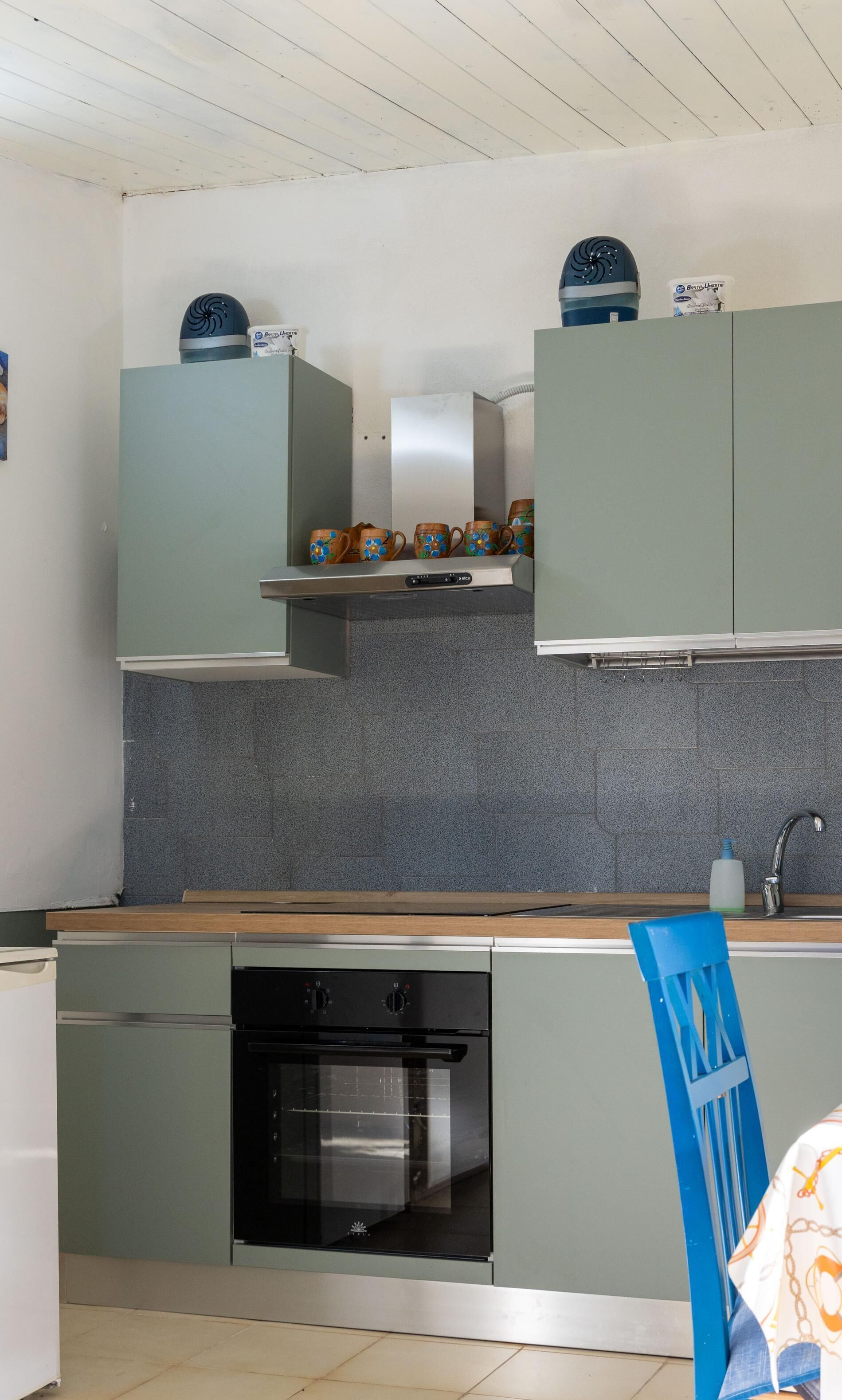 A kitchen with a dishwasher, oven, and a blue chair.