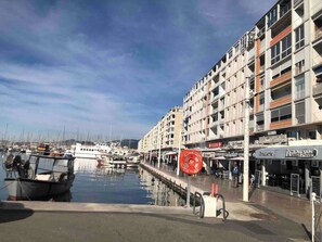 Satamassa on laivoja, rantapromenadi ja useita kerroksia sisältävä rakennus, jossa on liiketiloja.