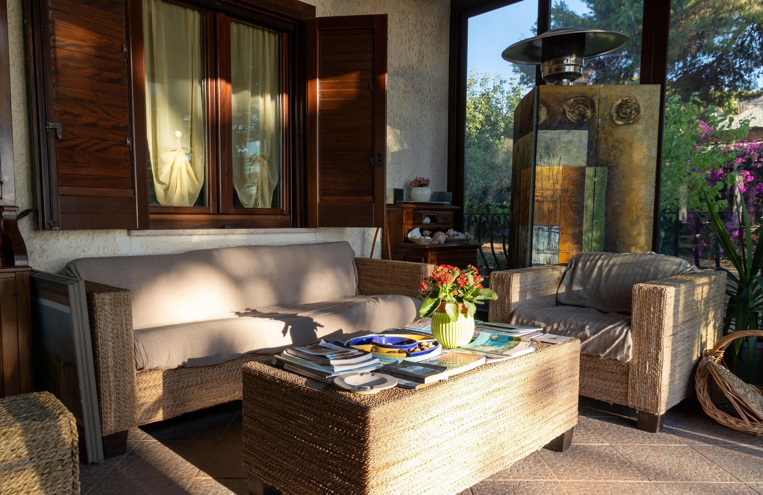 A furnished living area with a sofa, a wicker coffee table, and a decorative vase with flowers.