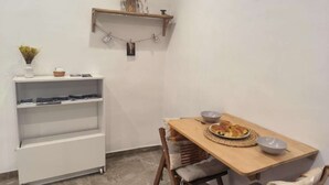 Un coin repas compact, avec une table en bois, des chaises et une petite étagère agrémentée d’objets décoratifs.