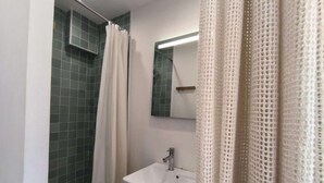 Une salle de bain avec une douche, un lavabo et un miroir.