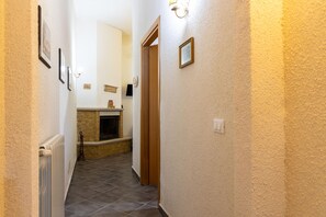 A narrow hallway with a radiator, a fireplace, and a door leading to another room. - Appartamento Lucentia Arancio - ... (Valderice)