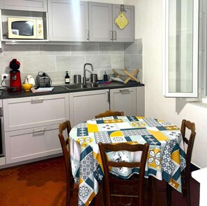 Una cucina accessoriata con forno a microonde, tostapane, bollitore, lavandino e un tavolo con tovaglia fantasia.