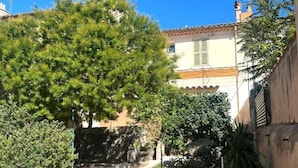 A residential area with a paved driveway, a tree-lined path, and a building with a tiled roof.