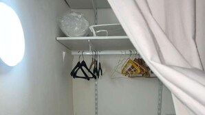 A closet with shelves and hanging space, a white door, and a tiled floor.