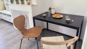 A dining area with a black table, wicker chairs, a white sofa, and a small plant on the wall. - Studio Horizon Toulon - near port & arsenal (Toulon)