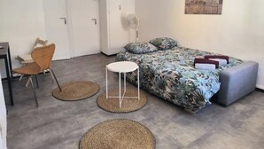 A bedroom with a bed, a chair, a small table, and a fan. - Studio Horizon Toulon - near port & arsenal (Toulon)