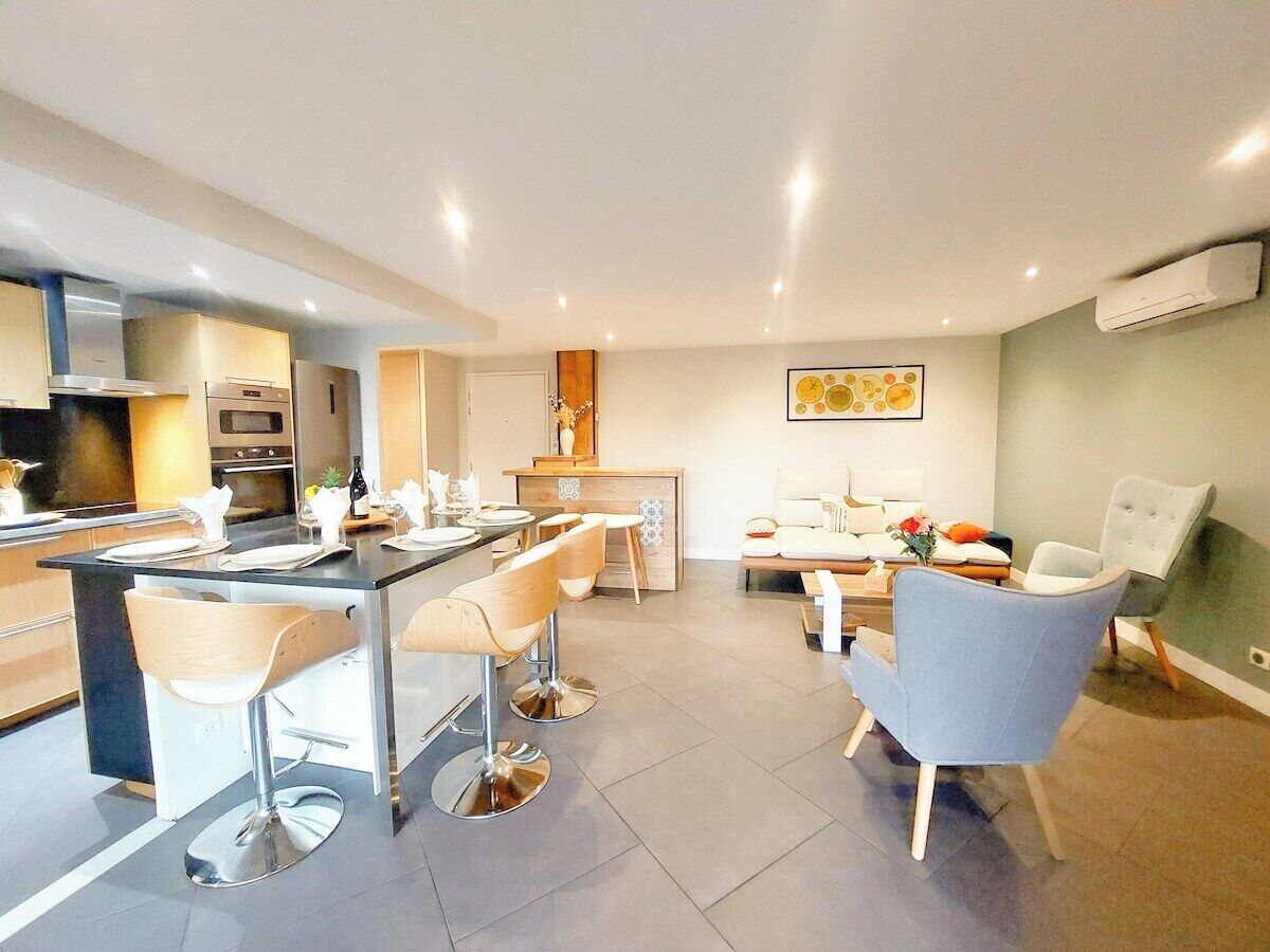 Une cuisine moderne avec un coin bar, des chaises de salle à manger, un canapé et une table basse.